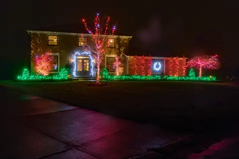 A brick house at night lit with red, white and green lights