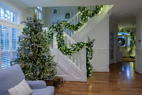 Lit garland on a staircase beside a Christmas tree