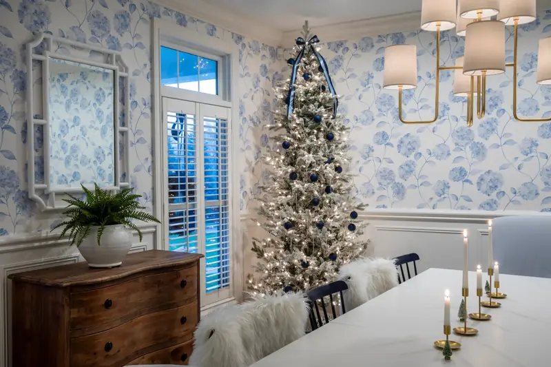 A living room decorated by English Gardens with a flocked tree, garland and wrapped gifts